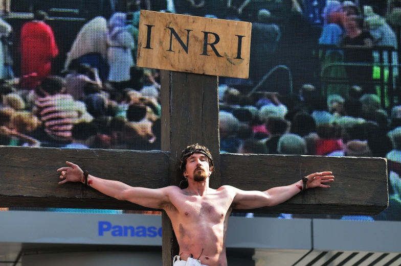 a man wearing  standing in front of a wooden cross