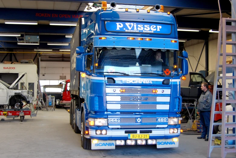 a blue truck parked inside a garage near another car