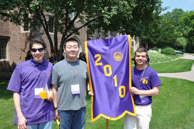 three men with purple jerseys and numbers holding a purple flag