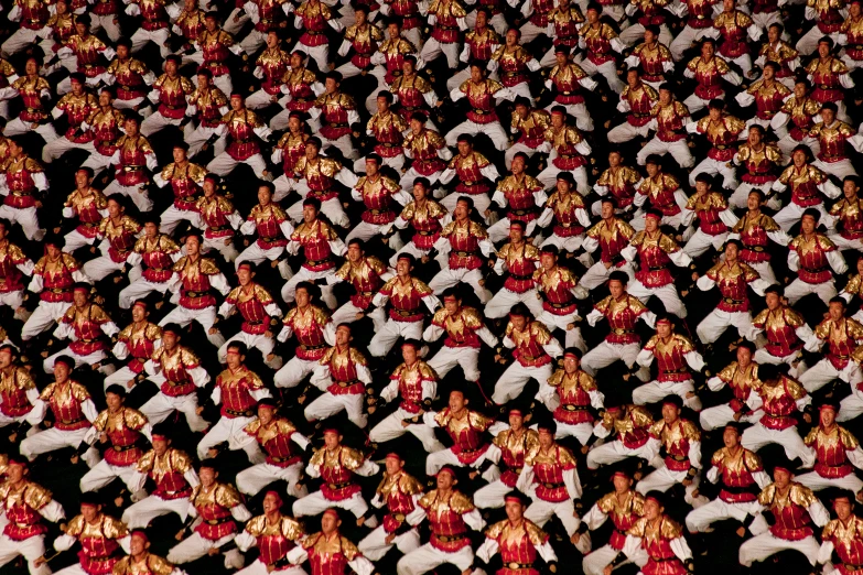 a crowd of red and gold statue with many figures in the background