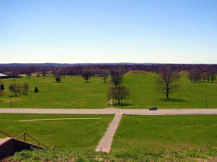 an aerial view of a grassy field near road