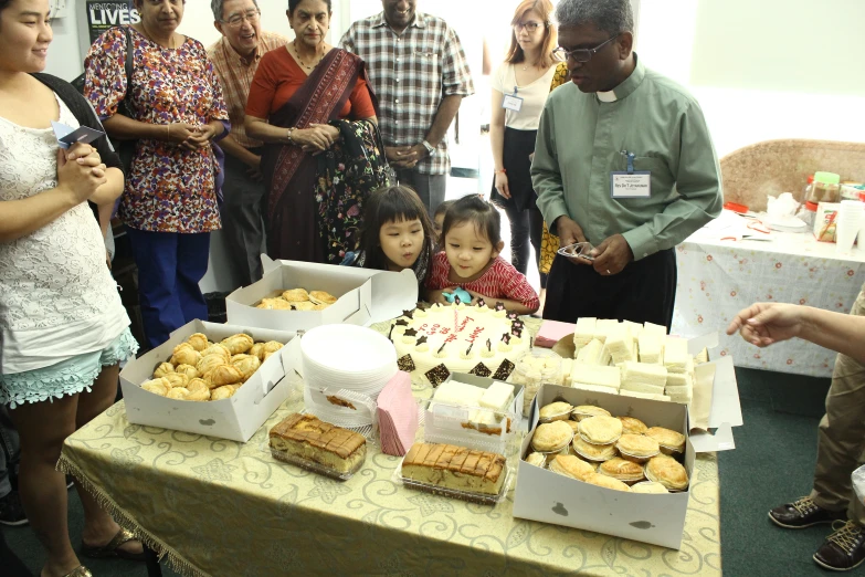 children look at cakes and pastries sitting on a table