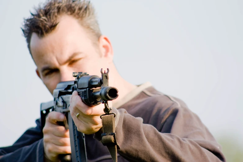 a young man is shooting a gun to the side