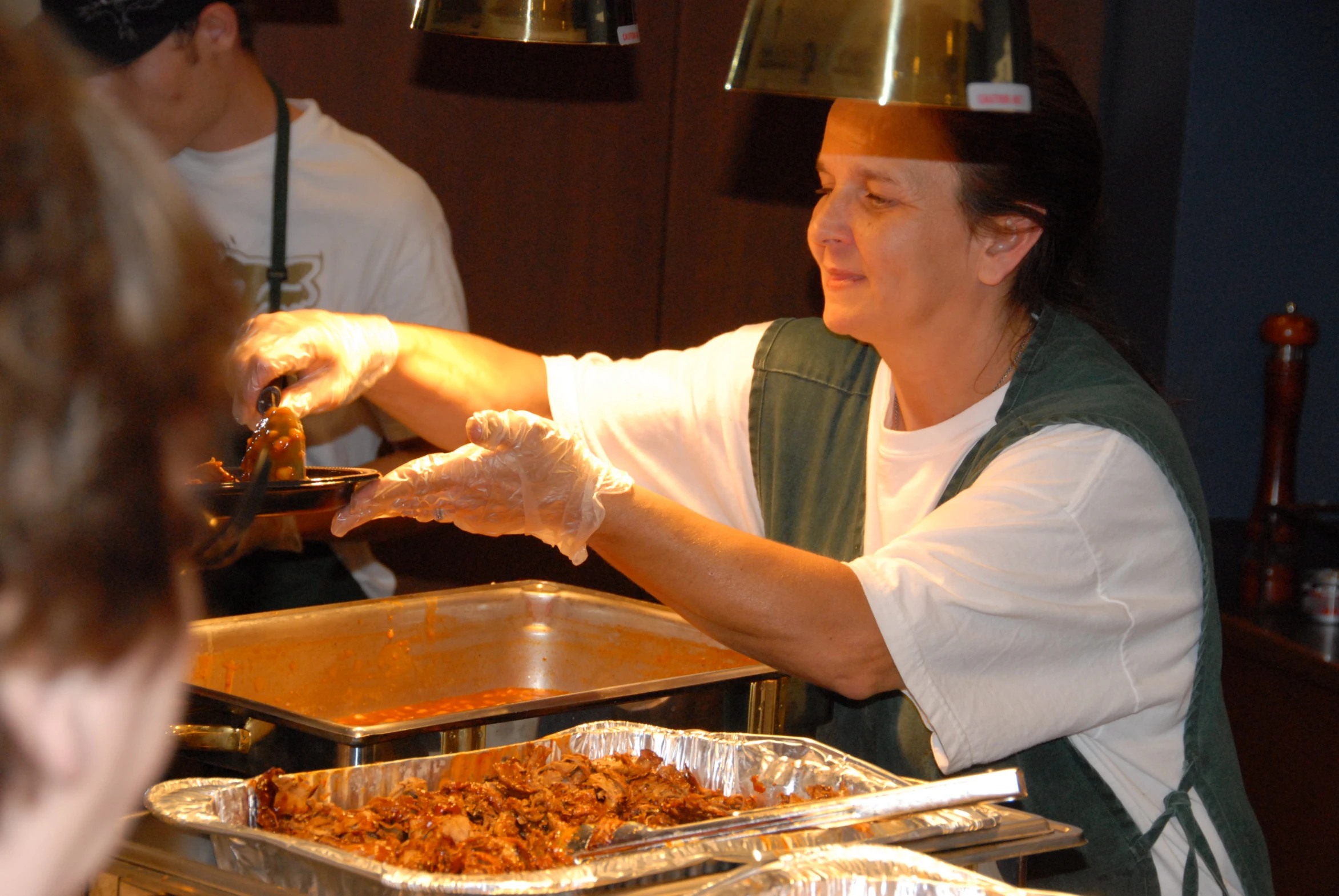 two women and one man standing next to each other making food