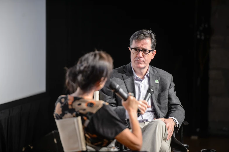 man and woman seated side by side speaking on stage