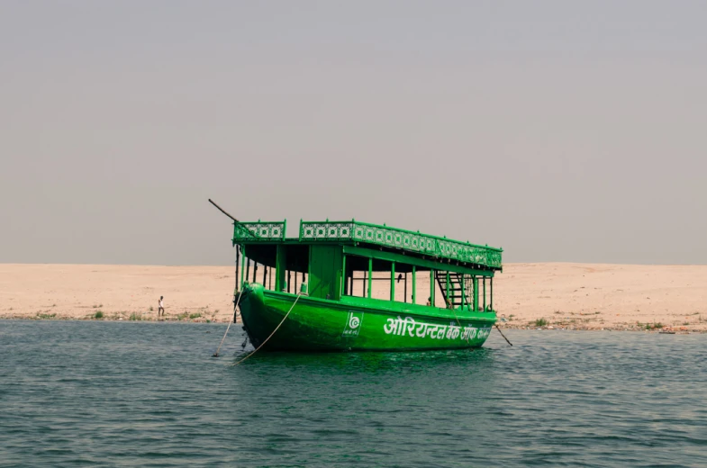 a green boat with two levels and stairs on water