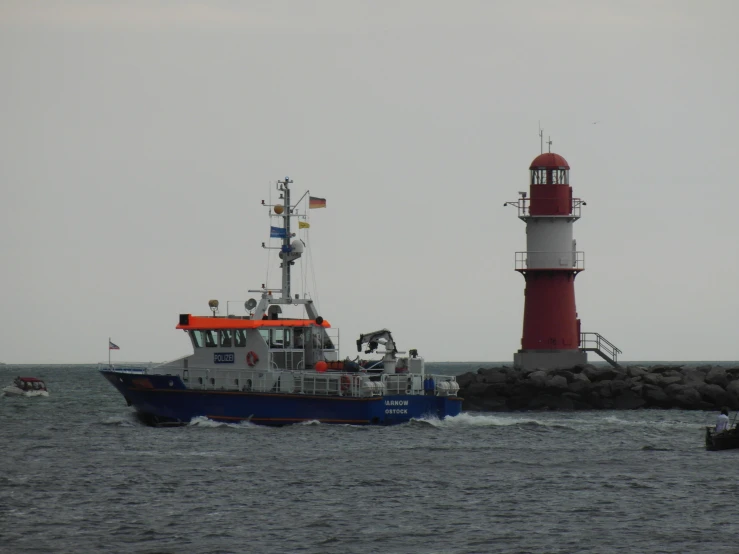 a small boat with red and white caps passes a lighthouse