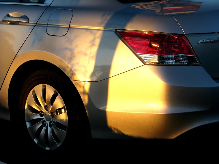 the rear end of a silver car is reflecting light on it