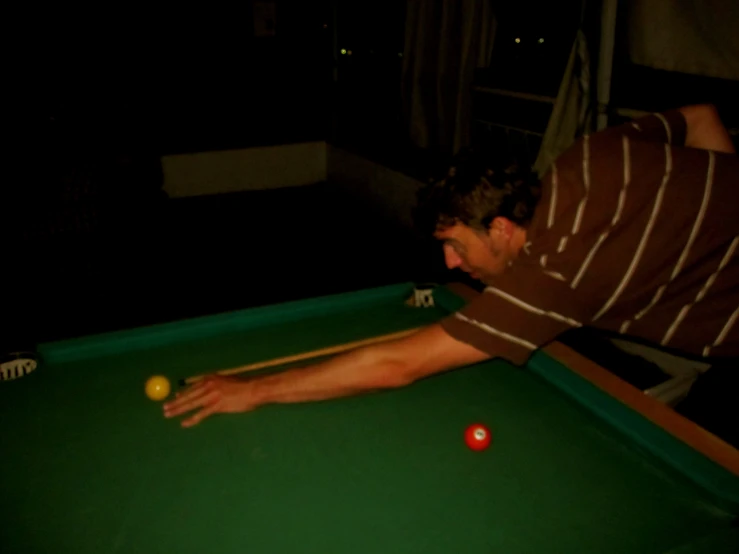 a man leaning over a pool table as he plays with his ball