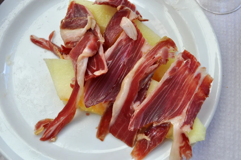 food sitting on top of a white plate covered in cheese and bacon