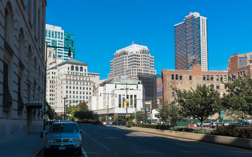 an automobile driving down a street lined with tall buildings