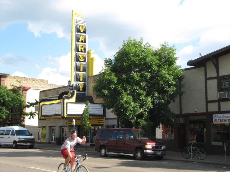 a person on a bicycle parked in front of a movie theater