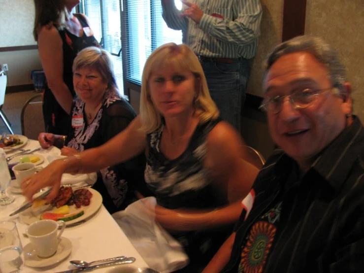 several people are sitting at a table with food and beverages