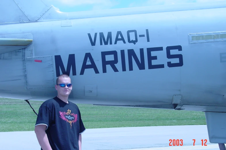 a man wearing a black shirt standing next to a blue plane