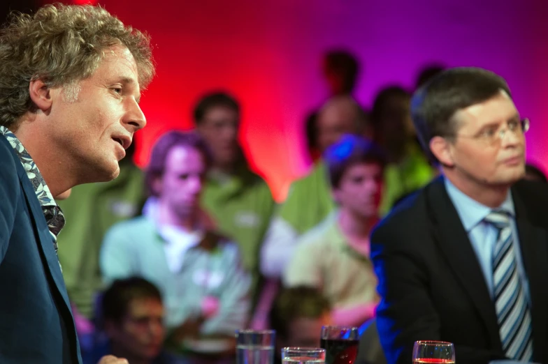 the men are talking while seated in front of the audience