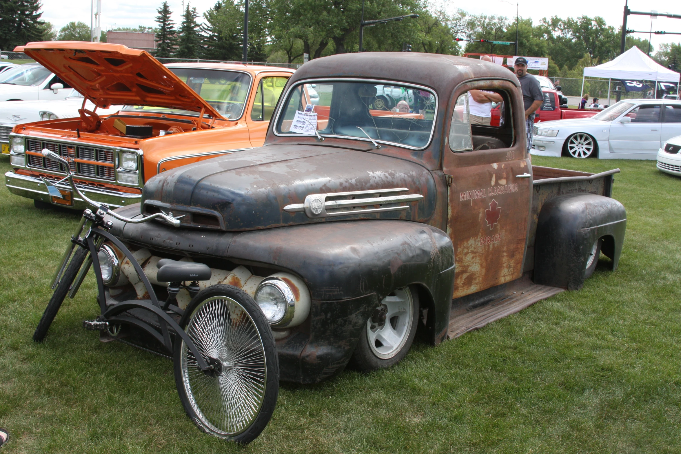 an old truck parked in the grass with a bicycle parked inside