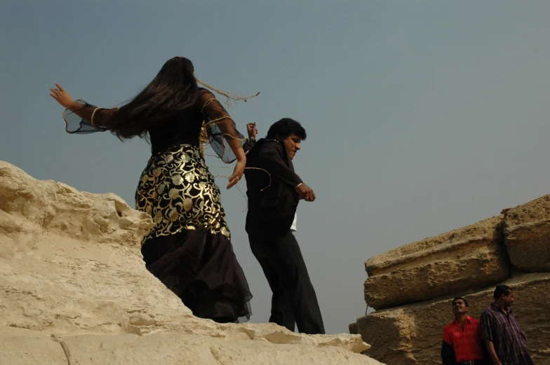 a couple of people standing on top of a sandy hill