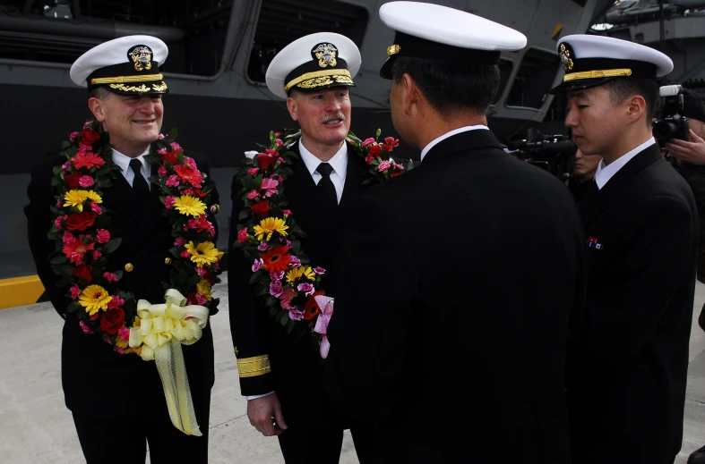 four people in naval uniforms standing near one another