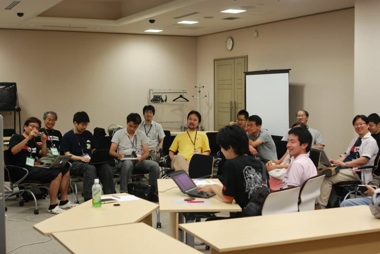 people sitting in chairs listening to a man speak into a microphone