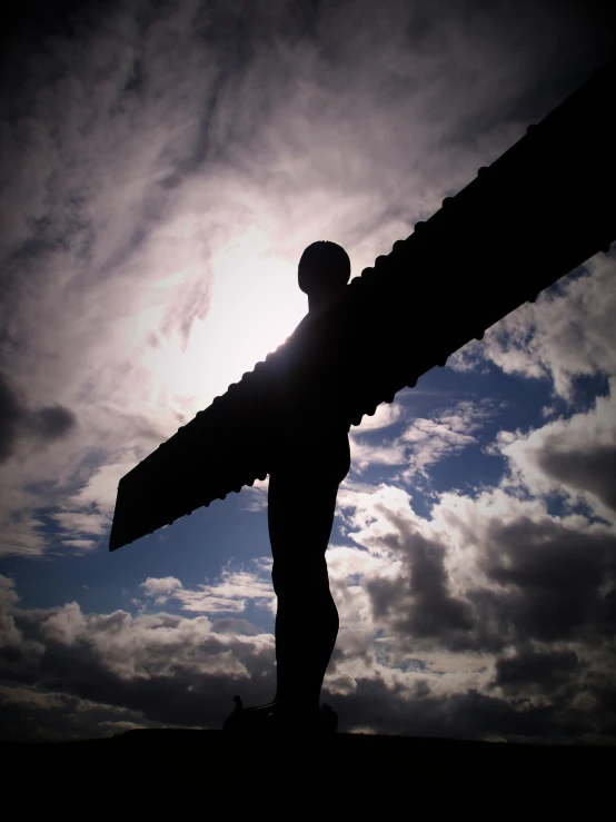 a statue of a man holding a large piece of wood in the sky