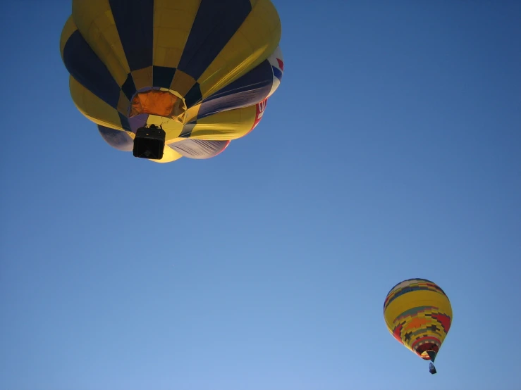 two large  air balloons are flying against the blue sky