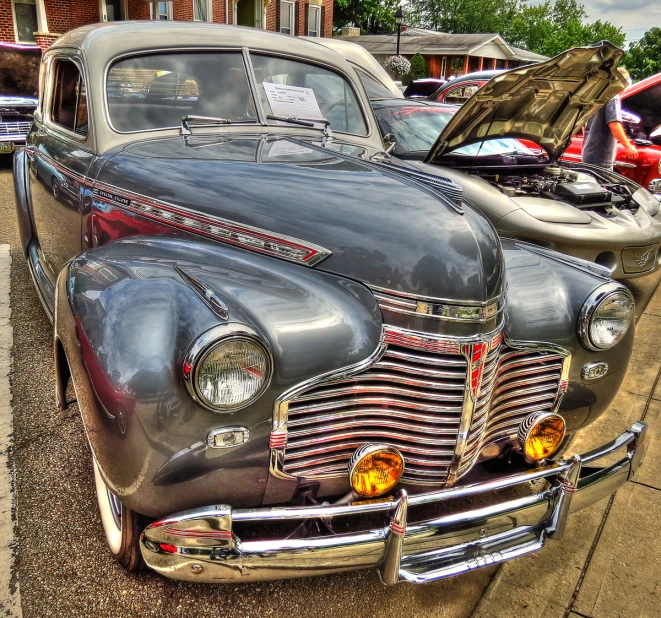 classic cars and their hoods parked at a car show