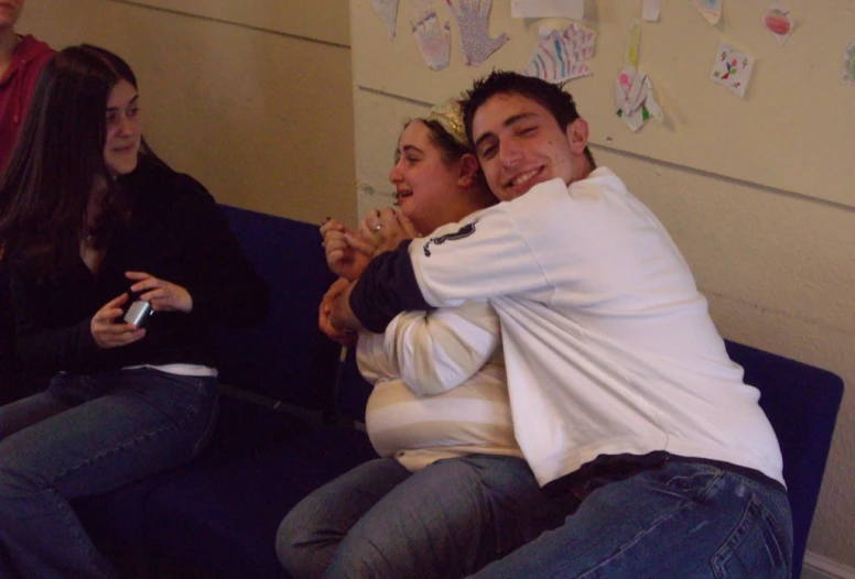 three people sitting on a blue couch in a room