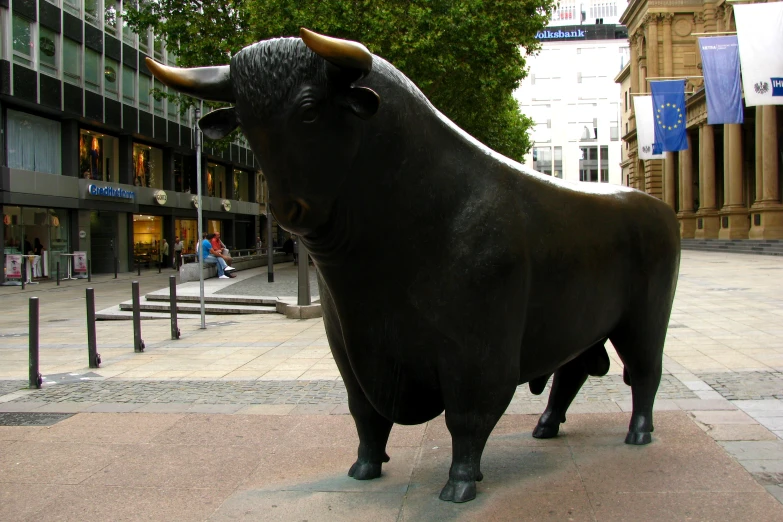 a bull statue stands in the middle of a city plaza