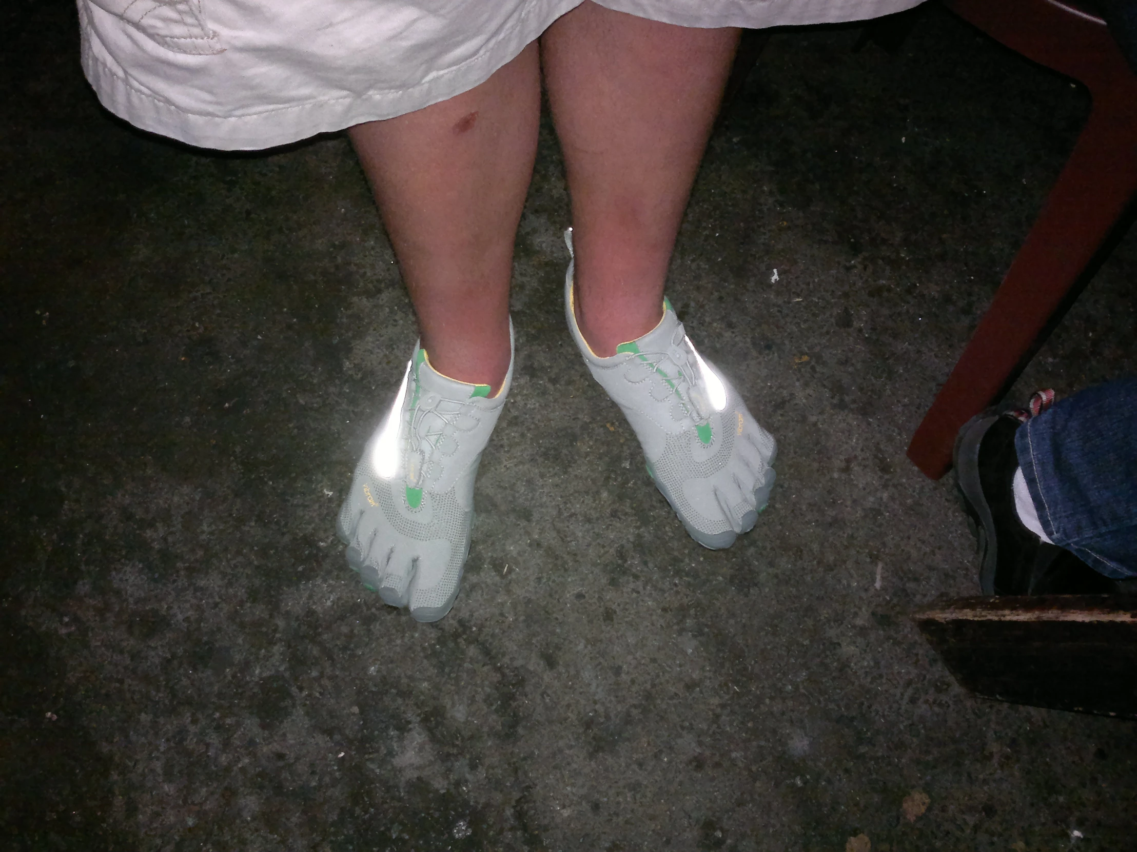 a woman's feet in white shoes near an object on the ground