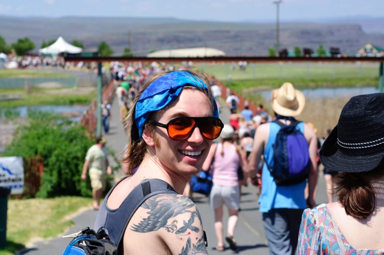 a person in sunglasses wearing a bandana and smiling for the camera