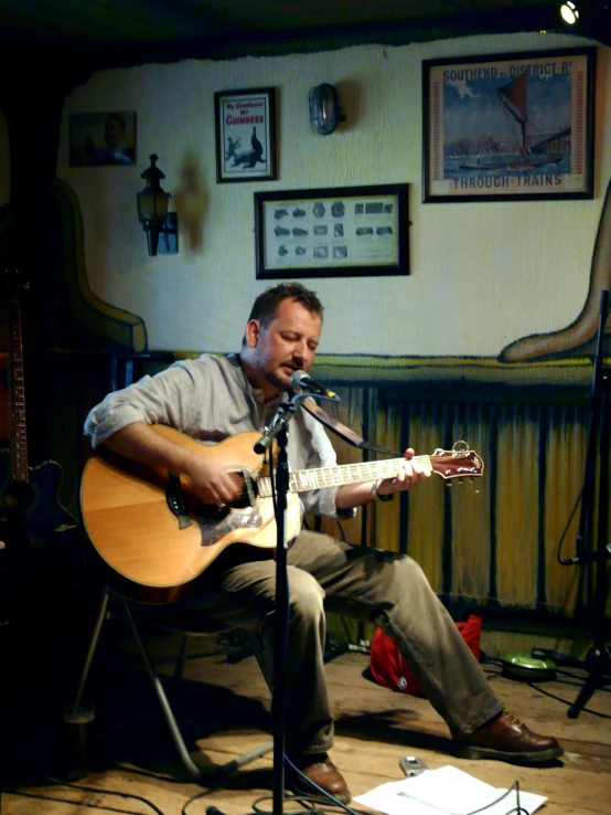 a man that is sitting on a chair playing a guitar