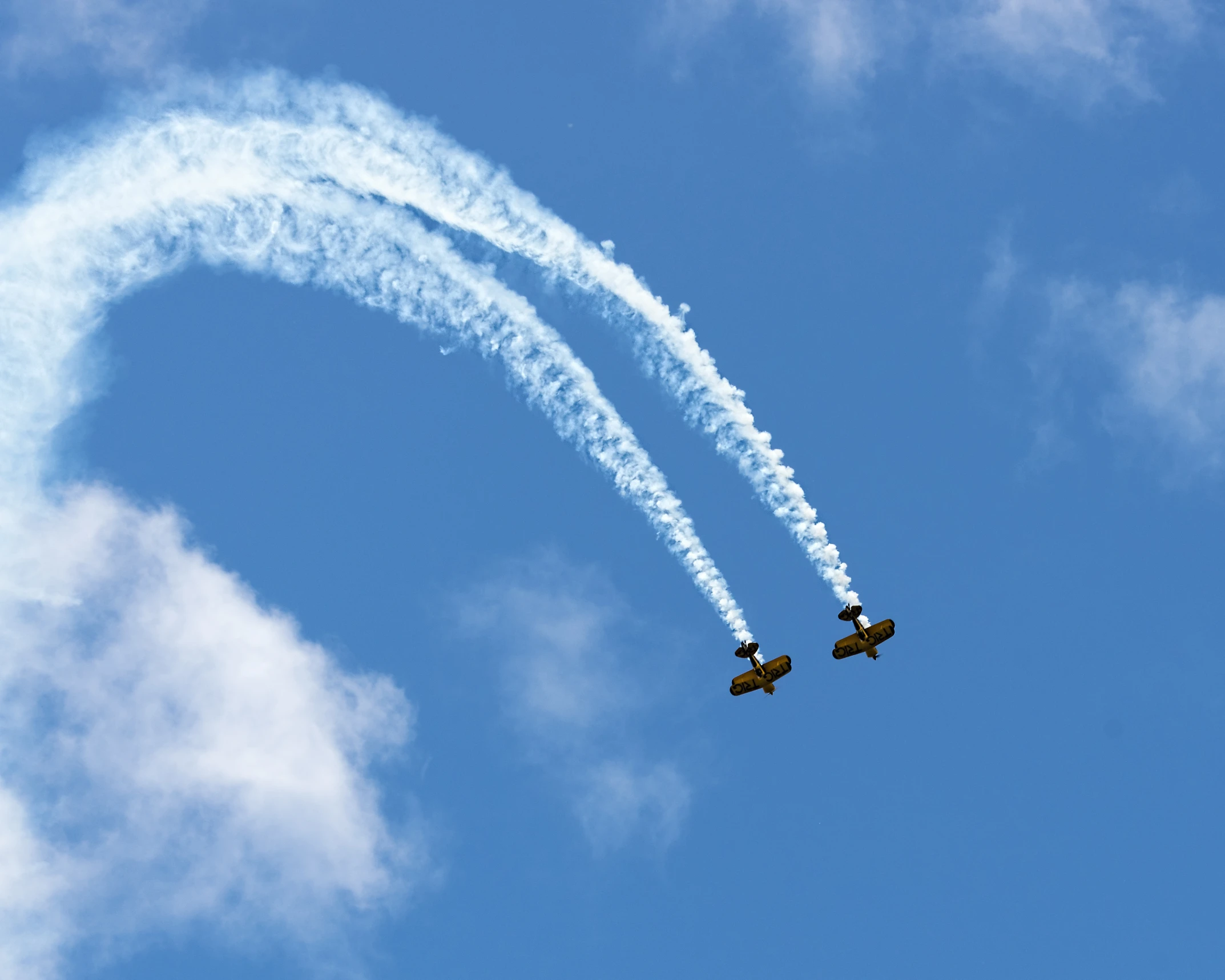 two airplanes are flying in the sky with contrails