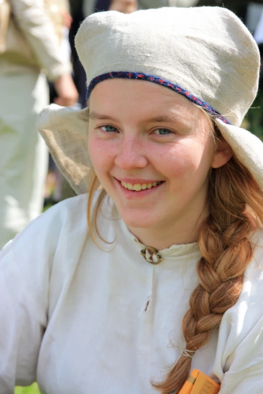 a smiling young woman in period clothing with ids on her head