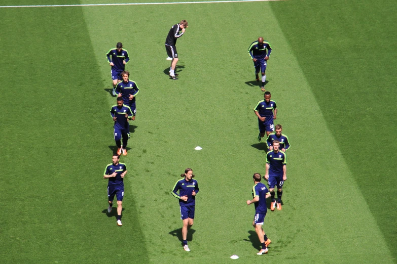 people wearing matching blue and yellow uniforms are on the grass during a soccer game