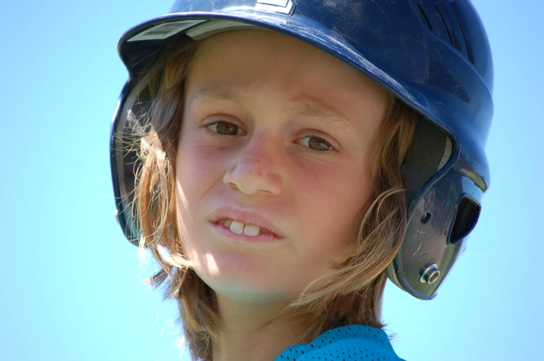 a  wearing a baseball helmet and looking at the camera