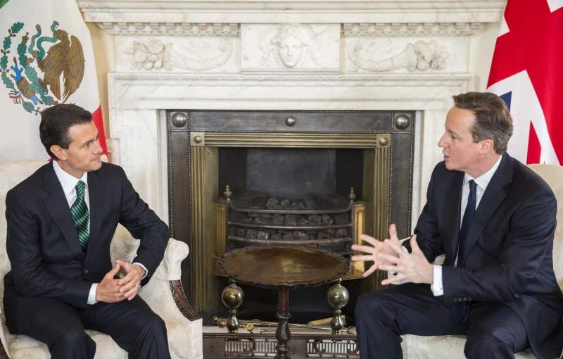 two men in suits sitting in front of an old fireplace