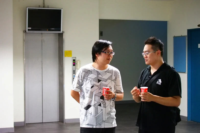 two guys standing in the middle of a gym room talking