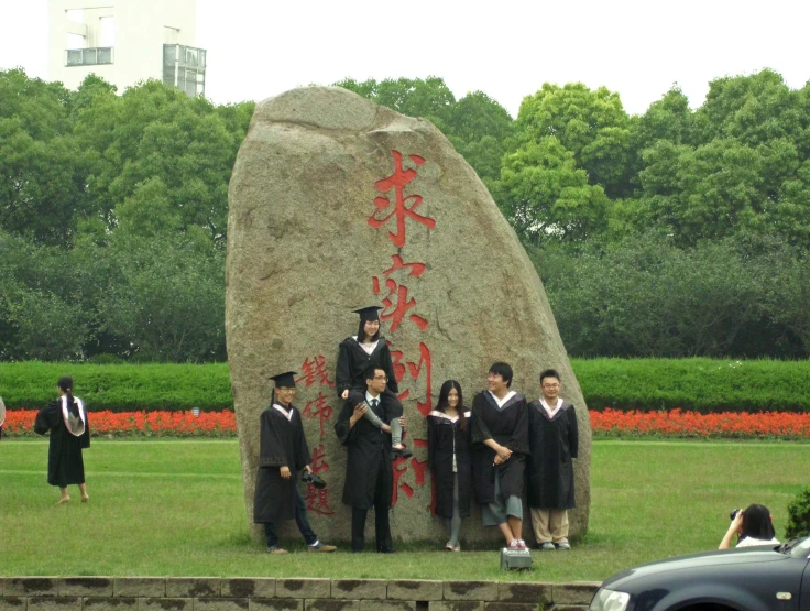 an asian sculpture at a park with some people in graduate's robes standing behind it