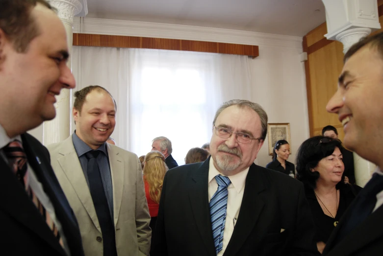 several men talking and smiling next to a curtain