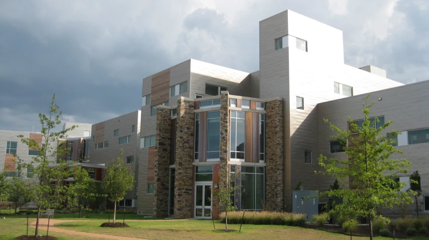 the view from across a lush green yard towards two modern buildings