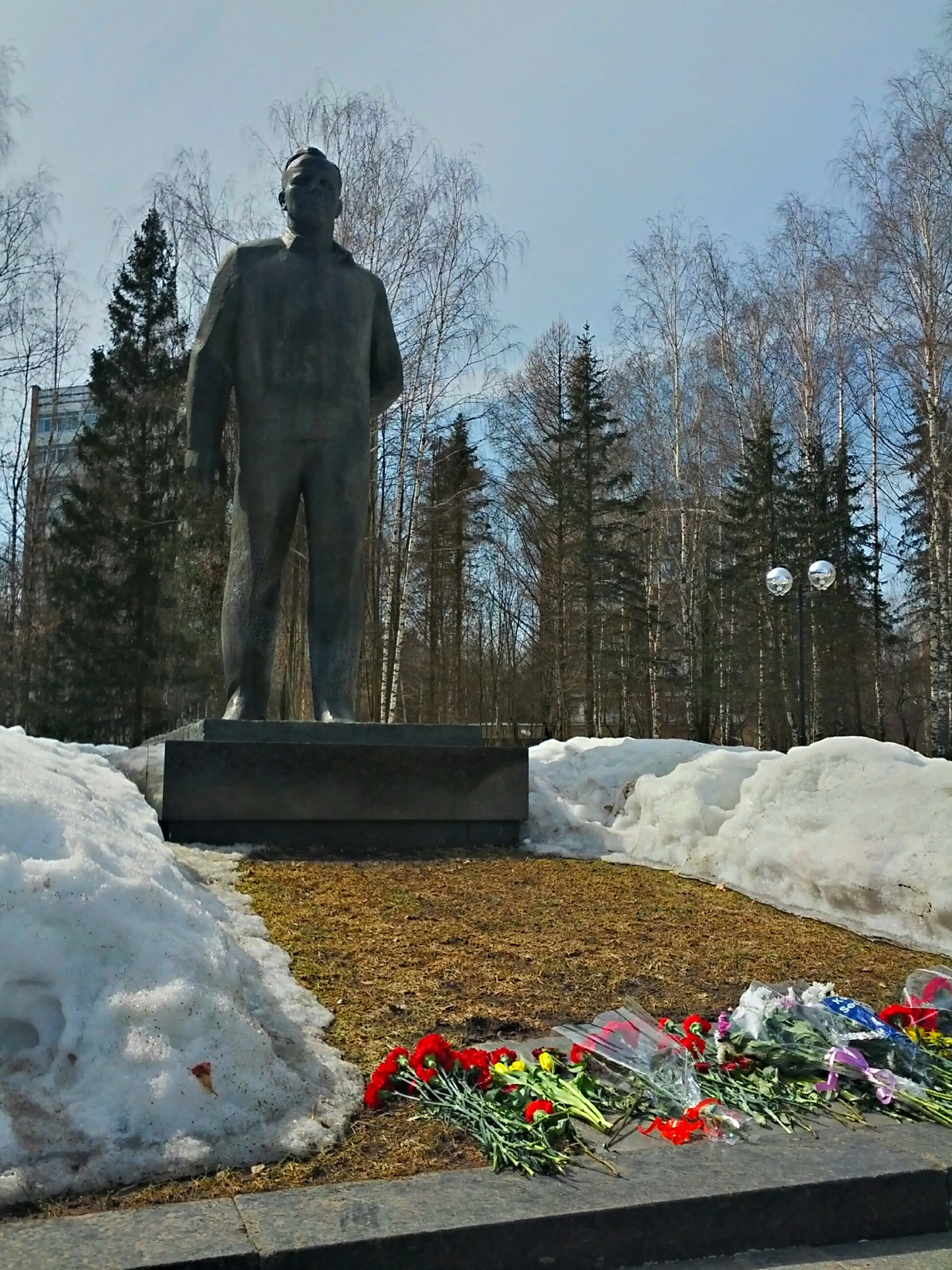 a large statue with some flowers on the ground