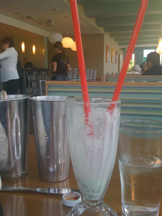 a couple of glasses with red straws sitting on top of a table