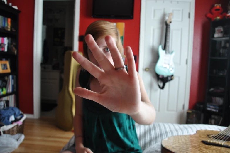 the woman is sitting on a bed with her hands raised in front of her