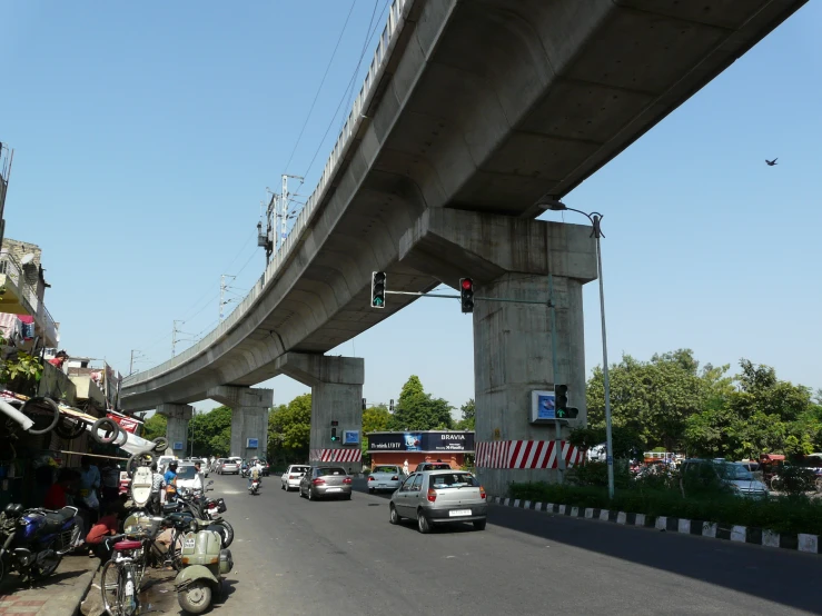 many cars traveling down a street under a tall bridge