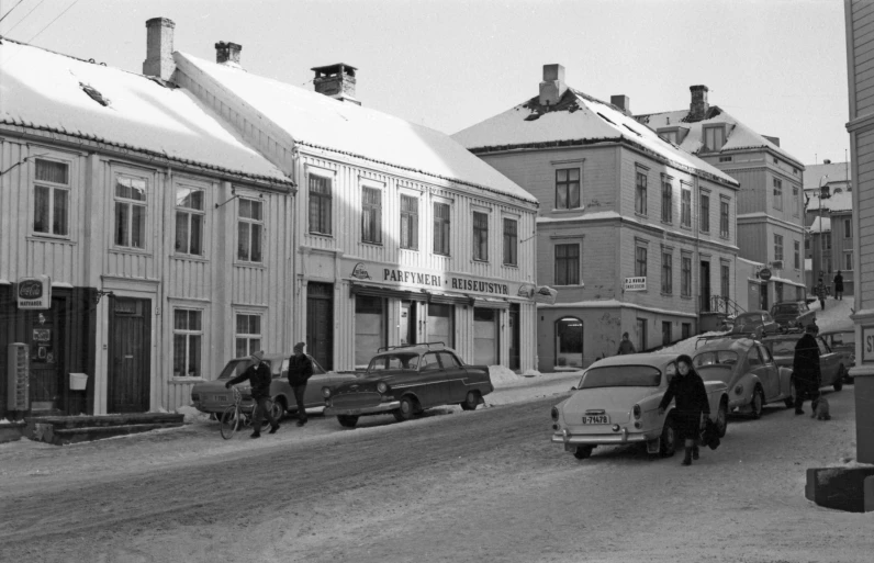 cars are parked along a city street in the snow