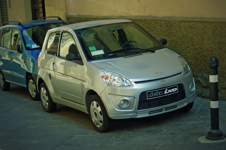 two small cars parked next to each other on a city street