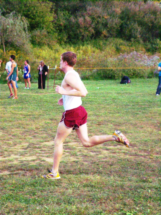 man running fast in a park while other people look on