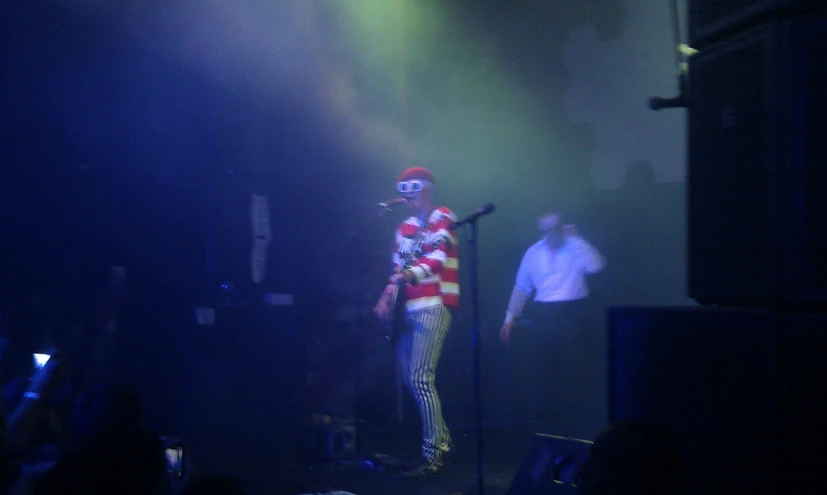 a creepy clown standing on stage with a microphone