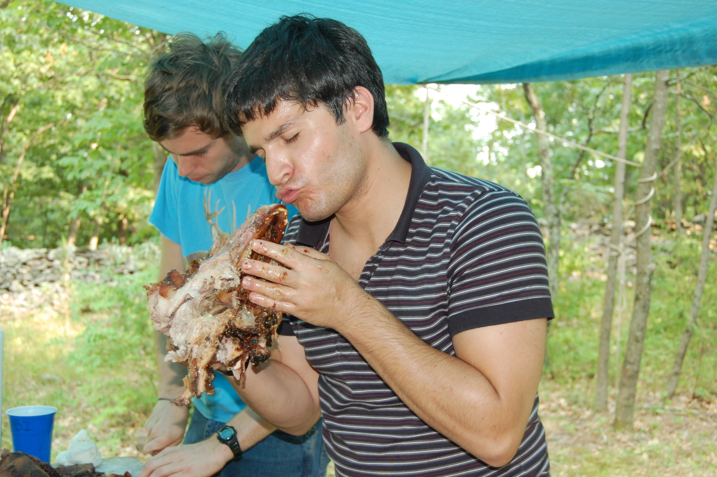 man eating a crab with two others on a camping site