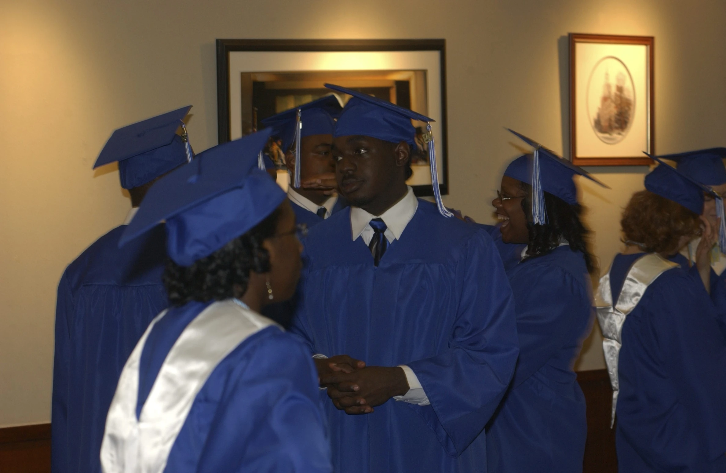 several graduates standing and talking together wearing blue caps and gowns